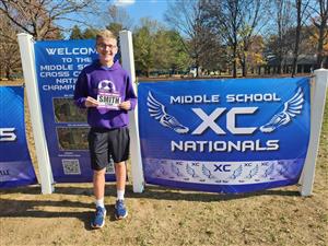 Ethan posing by national cross country meet sign.